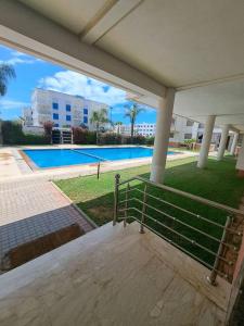 uma vista para uma piscina a partir do alpendre de uma casa em très bel appartement avec piscine em Minaret de Mansuria