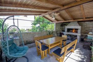 un patio con mesa de madera, sillas y chimenea en Fredi, en Mali Lošinj