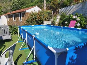 a blue swimming pool with chairs around it at Casa de Xisto in Arganil