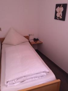a small bedroom with a bed with white sheets at Gasthof Hotel Bauer in Hersbruck