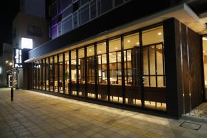 Dormy Inn Oita في أويتا: مبنى به نوافذ زجاجية كبيرة في الليل
