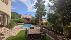 einen Hinterhof mit einem Tisch und Stühlen sowie einem Pool in der Unterkunft VILLAS COSETTE Villa Brava in Calonge