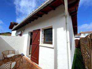 een wit huis met een rode deur en een patio bij Joli T2 à 1km de la chambre d'amour in Anglet