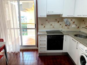 a kitchen with white cabinets and a sink and a dishwasher at Apartamento Pilartxo Zarautz in Zarautz