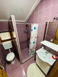 a pink bathroom with a toilet and a sink at Unaqua Apartments in Kulen Vakuf