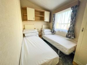 2 camas en una habitación pequeña con ventana en Lovely 8 Berth Caravan Nearby Scratby Beach In Norfolk Ref 50021f, en Great Yarmouth