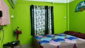 a bedroom with green walls and a bed and a phone at Shanti Kunj Homestay in Agartala