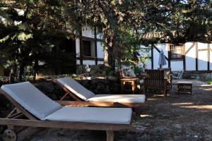Duas espreguiçadeiras e uma mesa debaixo de uma árvore em La cabaña del Burguillo em El Barraco
