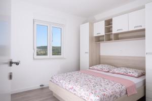 Apartman Franka في تروغير: غرفة نوم بيضاء بها سرير ونافذة