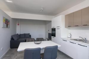 Apartman Franka في تروغير: مطبخ وغرفة معيشة مع طاولة وكراسي بيضاء