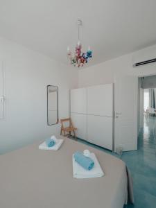 een witte slaapkamer met een bed en een kroonluchter bij Appartamenti San Lorenzo 1 in Reitani