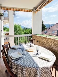 uma mesa com uma toalha de mesa azul e branca numa varanda em Annecy-le-Vieux Albigny - Proche Lac - Majord'Home em Annecy