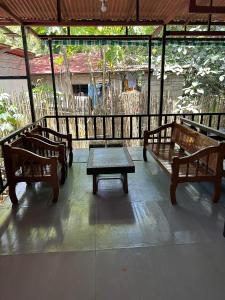 a porch with two benches and a table on it at Little John's Town Inn in Coron