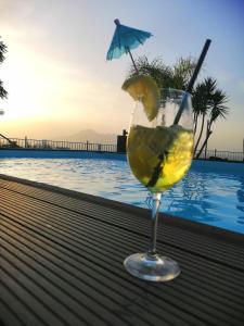 una copa de vino con una rodaja de limón frente a una piscina en Villa Mola Bed And Breakfast, en Corbara