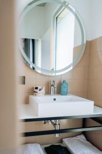 La salle de bains est pourvue d'un lavabo blanc et d'un miroir. dans l'établissement JOST Hôtel Bordeaux Centre Gare Saint Jean, à Bordeaux