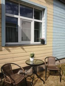 a patio with two chairs and a table and a window at Apartamenti Miera Osta in Liepāja