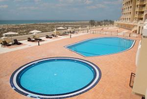 a large swimming pool next to a beach at Amazing sea view studio in Ras al Khaimah