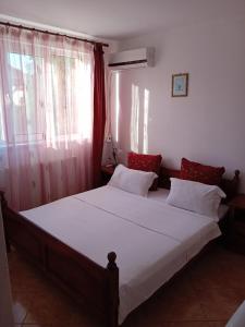 a bedroom with a large bed with white sheets and red pillows at casa andrei m in Eforie Sud