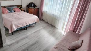 1 dormitorio con cama con almohadas rosas y sofá en Apartament blisko morza Carmen en Kołobrzeg