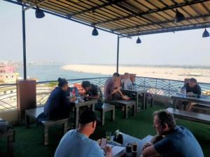 a group of people sitting at tables in a restaurant at Backpackers Park Varanasi in Varanasi