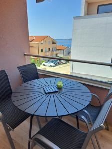 a table and chairs with a blue umbrella on a balcony at Apartma Šelih Mandre - Pag in Mandre