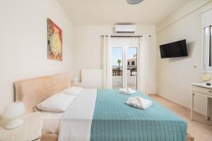 a white bedroom with a bed with a blue blanket at Villa Sophia-Elpis in Hersonissos