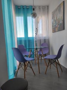 トロクス・コスタにあるEstudio El Faro IIのダイニングルーム(紫色の椅子、ガラスのテーブル付)