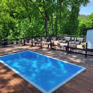 a blue swimming pool on a deck with tables and chairs at Villa Fortuna in Duszniki Zdrój
