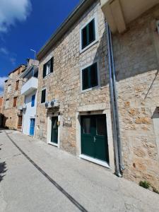 un edificio de piedra con puertas verdes en una calle en Studio Apartments Leut & Lanterna, en Vis