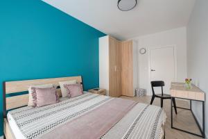 a bedroom with a large bed with a blue wall at Apartamenty stadion narodowy in Warsaw