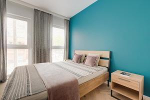 a bedroom with blue walls and a bed with pink pillows at Apartamenty stadion narodowy in Warsaw
