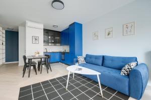 Apartamenty Stadion Narodowy في وارسو: غرفة معيشة مع أريكة زرقاء وطاولة