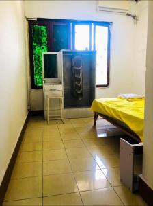 a room with a bed and a tv on a tiled floor at Vernice Backpacker Hostel in Vientiane