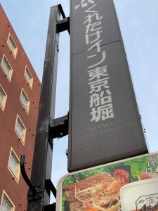Un cartello su un palo vicino a un edificio di Kuretake-Inn Tokyo Funabori a Tokyo