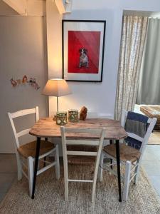 a dining room table and chairs with a dog painting on the wall at Charmant duplex vue mer et étangs ! Clim / Parking in Frontignan