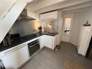 a kitchen with white cabinets and a sink at Charmant duplex vue mer et étangs ! Clim / Parking in Frontignan