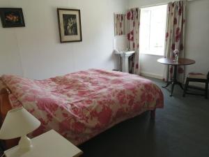 um quarto com uma cama, uma mesa e uma janela em The Old Stables of heritage Tregrehan Garden Cottages on South Coast em St Austell