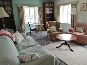 uma sala de estar com um sofá, cadeiras e uma mesa em The Old Stables of heritage Tregrehan Garden Cottages on South Coast em St Austell
