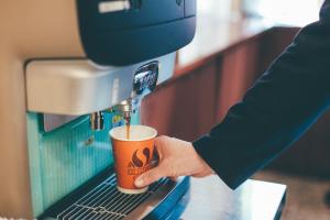 Kuretake-Inn Tokyo Funabori في طوكيو: شخص يصب القهوة في آلة صنع القهوة