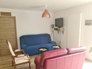 sala de estar con sofá azul y TV en Chez perlette, 
