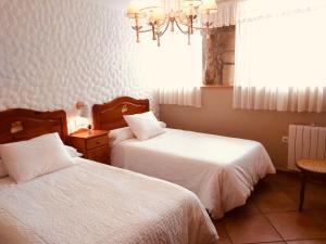 a bedroom with two beds and a window and a chandelier at Casa Pereiro playa de Esteiro in Viveiro