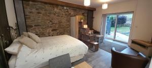 a bedroom with a bed and a stone wall at Wisteria Barn, Trewethen, St Teath, nr Port Isaac in Saint Teath