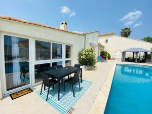 een zwarte tafel en stoelen naast een zwembad bij Magnifique appartement climatisé + accès piscine in Puissalicon