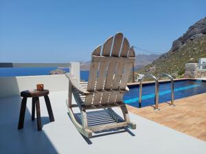 a wooden rocking chair sitting on a balcony with a pool at Villa Kairos- Aegean Sea in Masouri