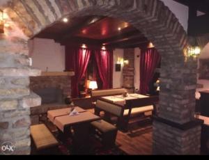 ein Wohnzimmer mit Tischen und einer Steinmauer in der Unterkunft Motel Konak in Sarajevo