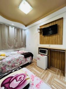 a bedroom with two beds and a flat screen tv at Pousada Cantinho das Flores in Penha