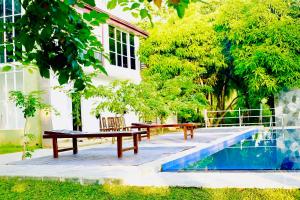 a picnic table and bench next to a pool at Shanthi Villa Resort in Anuradhapura