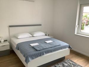 a white bedroom with a bed and a window at Apartments Jozef in Vodice