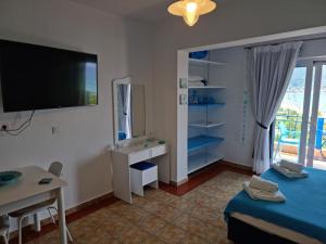 a room with a bed and a desk and a television at Wild Seagull in Vasiliki