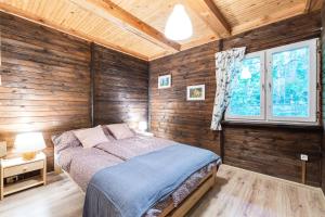 a bedroom with wooden walls and a bed in a room at Chata 'Leśne Kurki' in Kurki